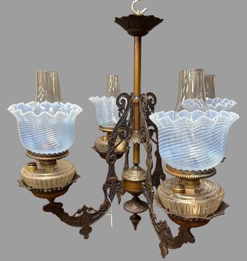 Four Arm Oil Lamp Chandelier With Blue Opalescent Shades: This four-arm oil lamp chandelier features ornate detailing and blue opalescent swirl shades. One of the lamp reservoirs has a visible crack, but the chandelier remains a stunning display piece. In-ho