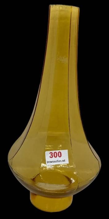 Amber Glass Octagonal Lamp Chimney: This amber glass lamp chimney features an octagonal shape, a 2-inch diameter base, and a height of 8 1/2 inches. Some roughness is evident along the rim edges. An ideal piece for restoration projects