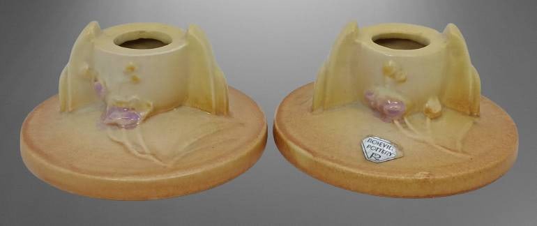 Roseville Ixia 1125-2" Candleholders: Roseville Ixia 1125-2" candleholders featuring floral motifs and a creamy yellow pastel glaze. Free of chips, cracks, or repairs. In-house shipping available.