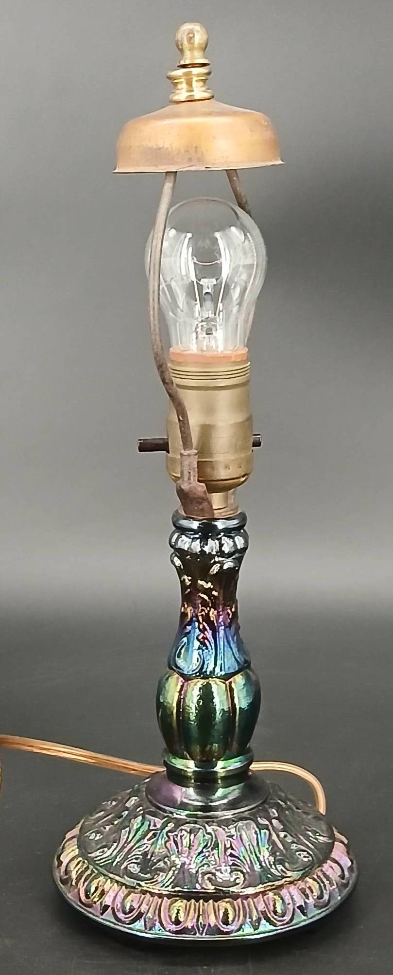 Iridescent Carnival Glass and Brass Accent Lamp: Table lamp featuring an iridescent carnival glass base with an Art Nouveau aesthetic and brass-colored elements, including a harp and finial. Stands 14" tall. Operates with a single bulb (included). T