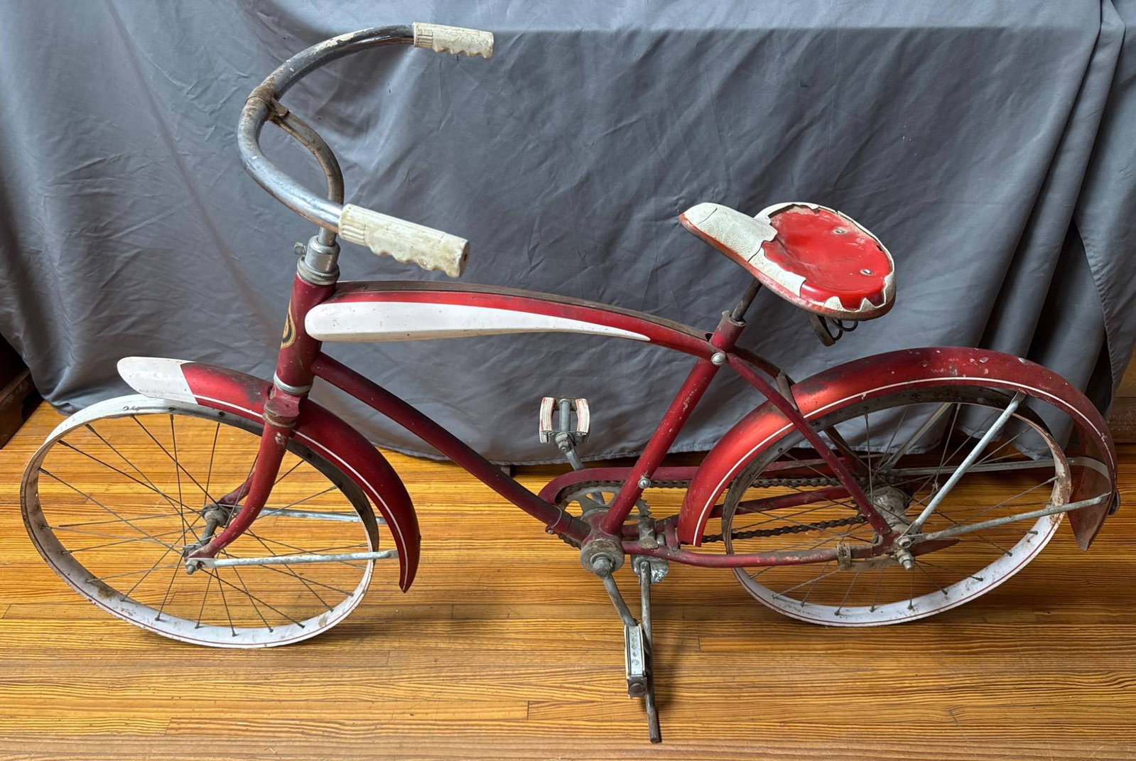 Red Sears Bicycle with Distressed Finish: Red metal Sears-designed vintage bicycle featuring white highlights. Distressed finish with paint loss and wear on the seat and frame. Includes original pedals, handlebars, and fenders. **BROWN AUCTIO