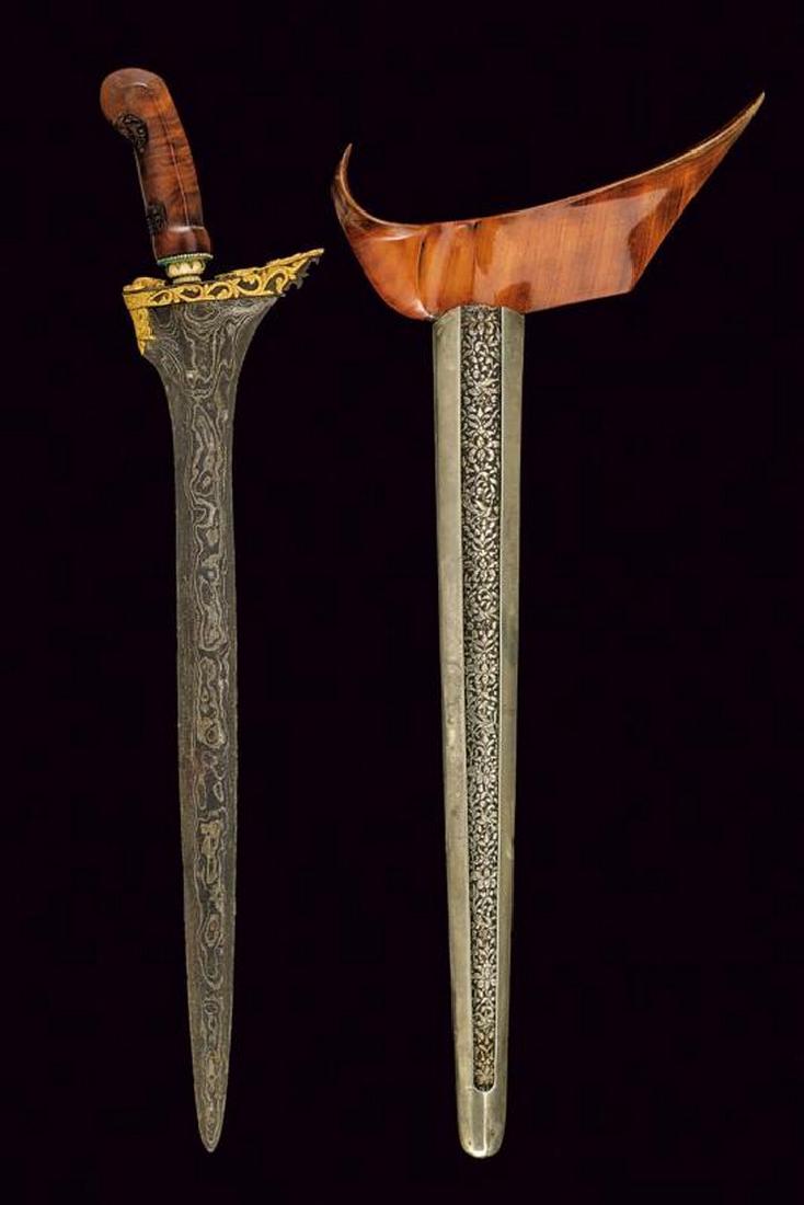 A gilded kris: dating: Late 19th Century provenance: Indonesia, Double-edged blade, in fine pamor, of lenticular section, enlarged and asymmetrical at the base, with ganja finely decorated in bas-relief with gold-in