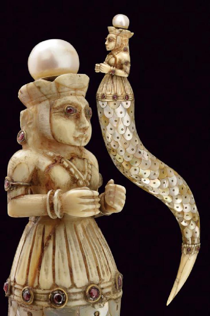 A very nice powder flask: dating: Second part of the 20th Century provenance: India, Undulated body, covered with mother-of-pearl plates, bone upper part, finely chiselled with a female figure, decorated with small, red stones