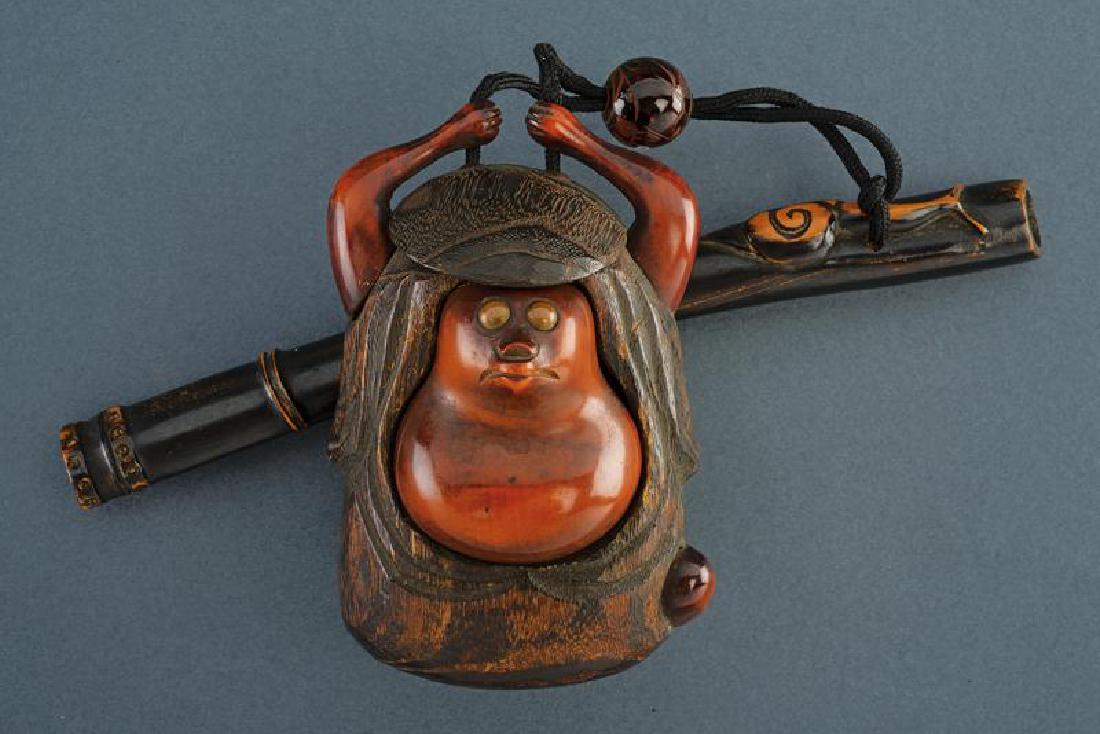 A tobacco box: dating: First half of the 20th Century provenance: Japan, Wooden, shaped as a monkey. Together with a wooden holder (without mouthpiece) shaped as a bamboo, decorated with a snail. height 12 cm.