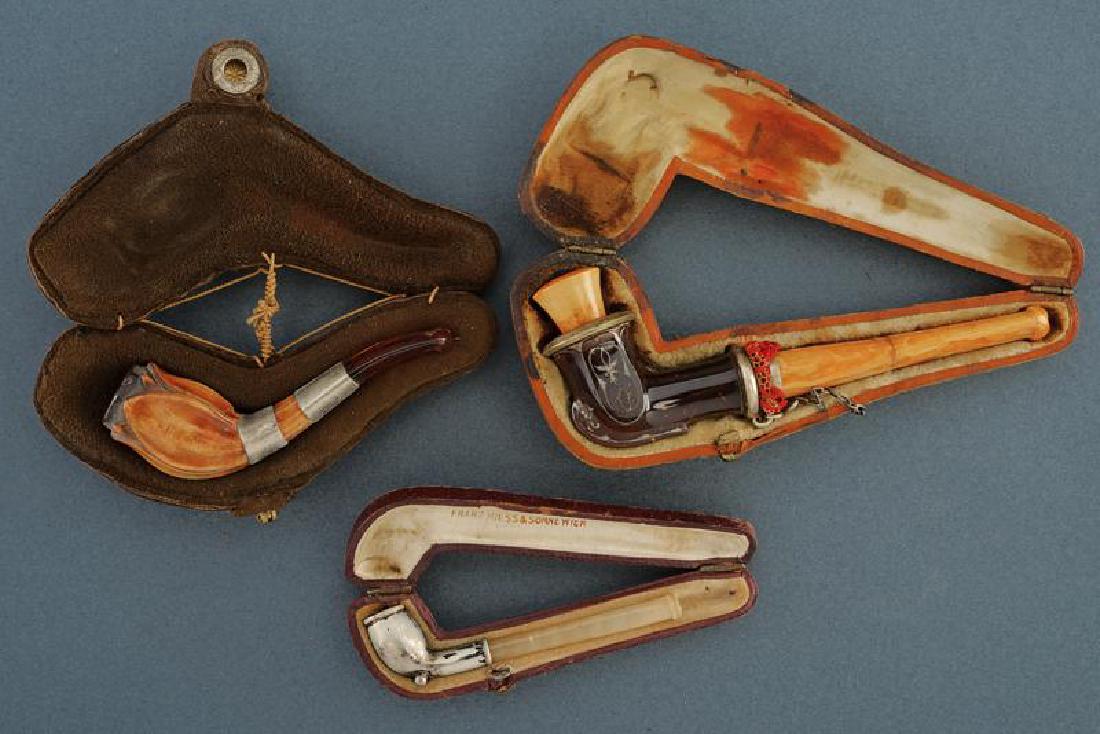 A lot of three cased mouth pieces: dating: First half of the 20th Century provenance: Europe, All shaped as a pipe, one in silver, one is wooden, embossed, and one in horn, decorated in silver with amber mouth, Marking 'FRANZ HIESS & S