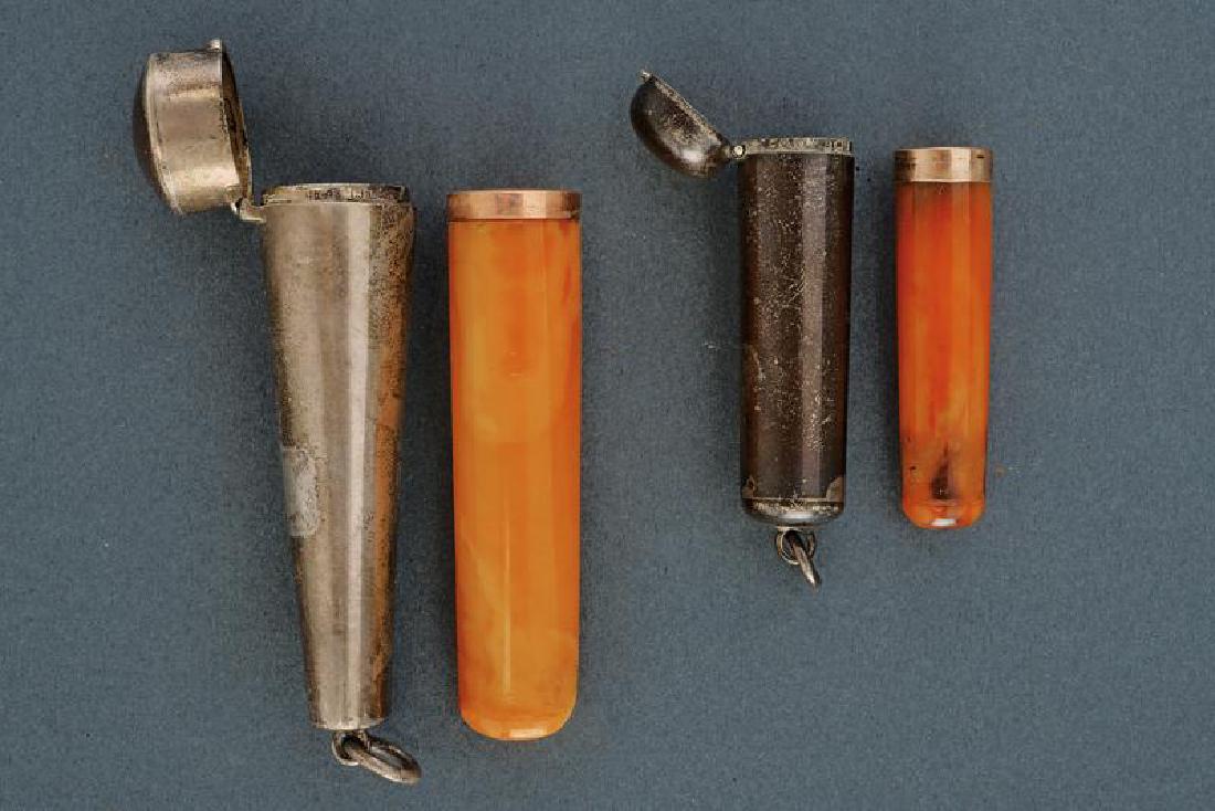 A lot of two cigarette holders: dating: First half of the 20th Century provenance: England, In amber, one with golden ring marked '585' and one with gilded, silver ring. Both in silver cases, stamped on the cover. length 5 - 7.2 cm.