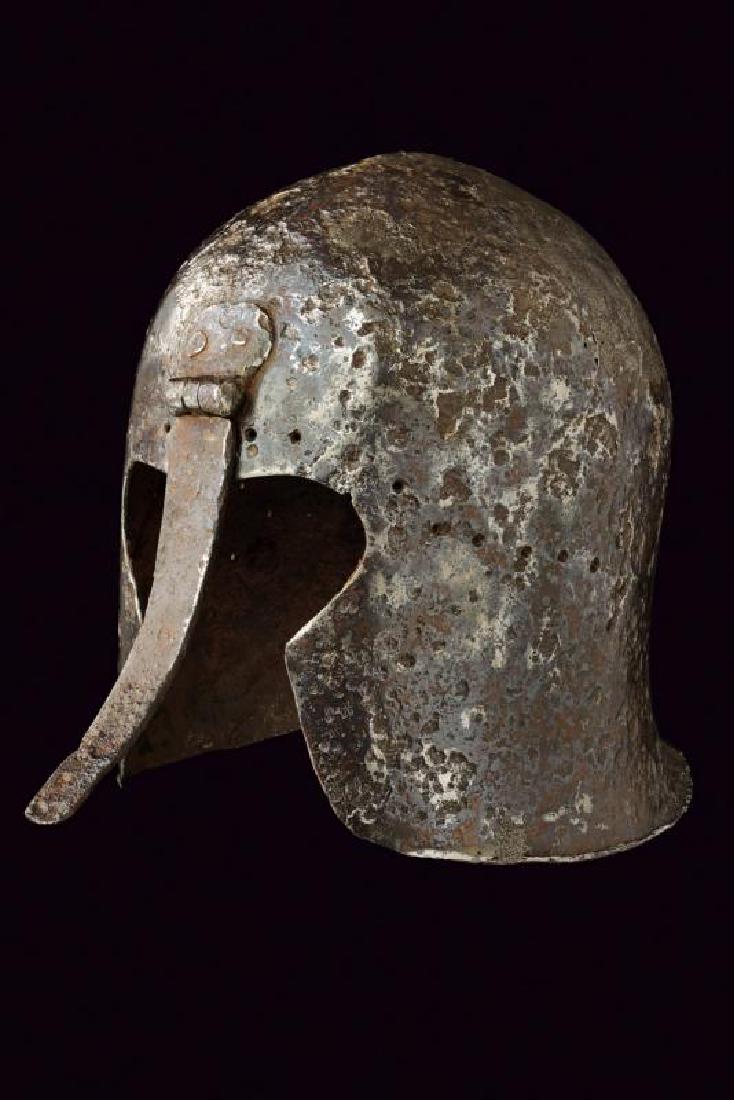 A nasal barbute in Corinthia style: dating: 15th Century provenance: Italy, In iron, in one piece, ribbed in the center and with facial opening with riveted and raisable nose-piece, which recalls the antique Greek helmets. A row of hole