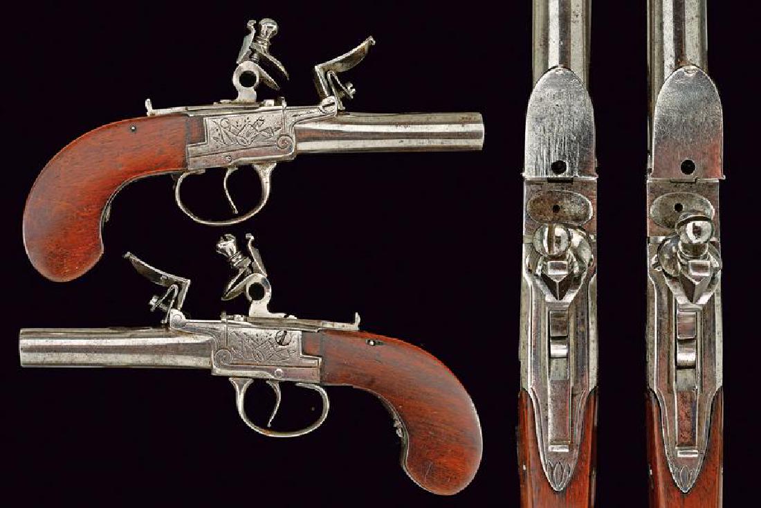 A pair of flintlock pocket pistols: dating: First half of the 19th Century provenance: France, Round, smooth-bore, 11 mm cal. barrels; box lock type frames engraved with trophies, upper cocks with safety lock. Iron, engraved trigger gua