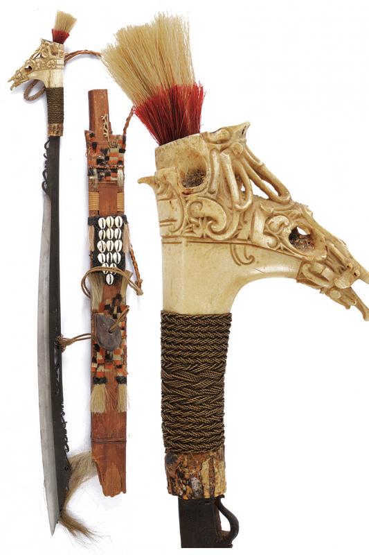 Mandau: dating: First half of the 20th Century provenance: Kalimantan, Fine, long and heavy blade of typical shape, chiselled and pierced on the back and at the base. Bone hilt, richly embossed, base with met