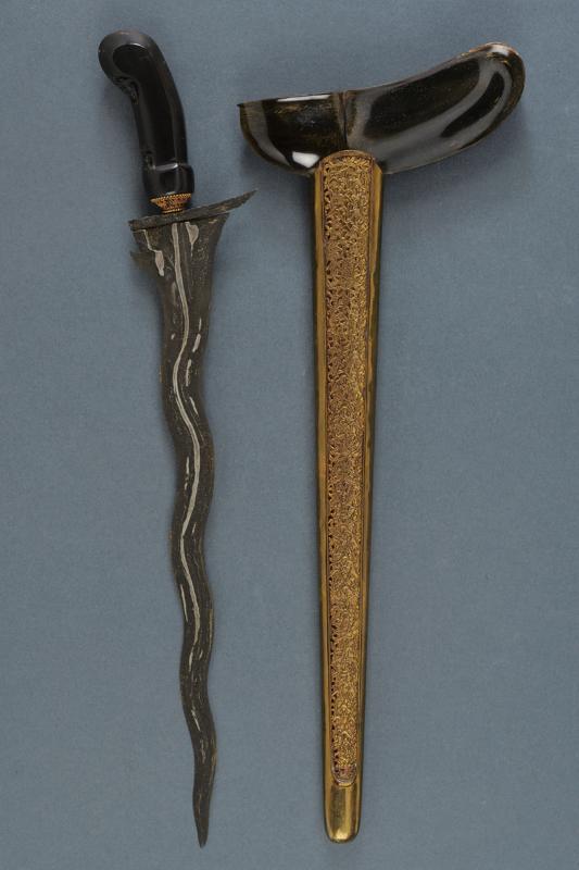A kris: dating: 20th Century provenance: Giava, Undulated double-edged blade, in fine pamor, with chiselled and grooved base. Wooden ukiran, slightly embossed with floral motifs, brass mendak, decorated with 