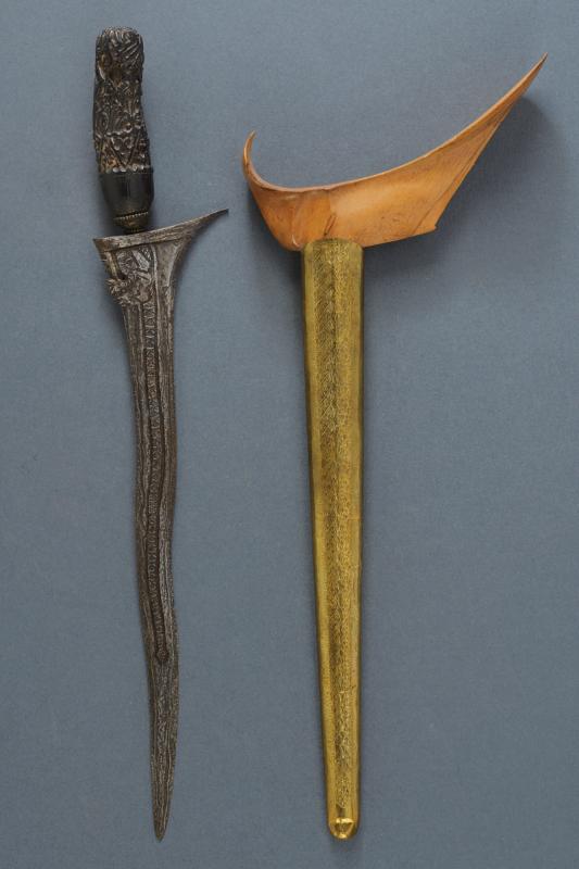 A kris: dating: 20th Century provenance: Yogyakarta, Undulated double-edged blade, in fine pamor, base chiselled with a dragon and grooved. Wooden ukiran, slightly embossed with floral motifs, brass mendak. W