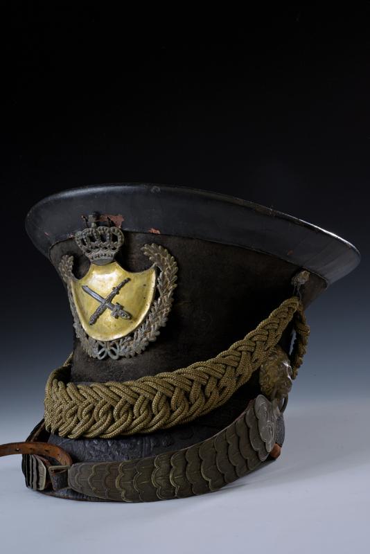 A town guard helmet: dating: 1830-40 provenance: Bavaria, Body covered with black felt, with leather peak, band at the base and visor. Partially pierced badge on the front. Chin-strap with flat scales, engraved on a lion'