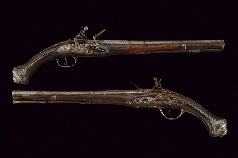 A pair of flintlock pistols: dating: about 1820 provenance: Turkey, Long, smooth-bore, three-stage, 15 mm cal. barrels, first octagonal and finely chiselled, then two, round segments; flintlocks, decorated en suite. Wooden, full 