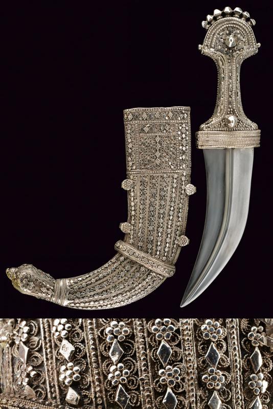 A silver mounted Jambiya: dating: First half of the 20th Century provenance: Arabian Peninsula, Wide, curved, double-edged blade with central raiser. Grip covered with silver foil and decorated with filigree. Wooden scabbard, 