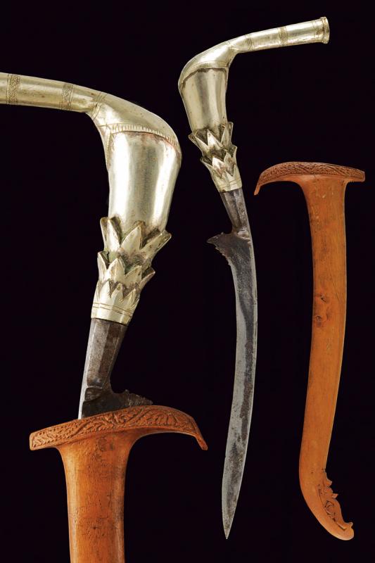 Rencong: dating: circa 1900 provenance: Sumatra, Slightly curved, single-edged blade, base chiselled with a curl and faceted knot. Silver, partially engraved grip of typical shape. Wooden scabbard, embossed at