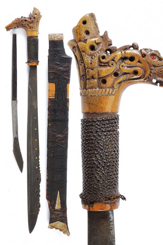 Mandau: dating: 20th Century provenance: Kalimantan, Single-edged blade of typical shape, chiselled and pierced on the back near the foible. Horn grip, richly pierced and embossed, decorated with read beads, 