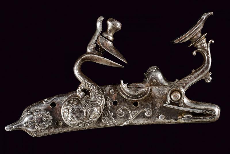 A beautiful snaphance lock: dating: late 17th Century provenance: Bologna, Plate and cock finely chiselled with masks, mystic figure and floral motifs. Sliding pan cover. Signed inside 'Il Pozzi Sabbioni'. Small parts of mechani
