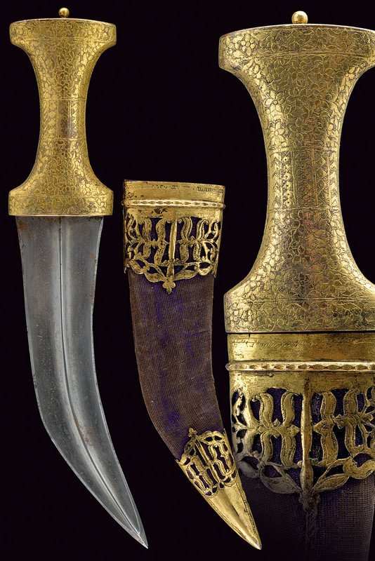 A jambyia: dating: 19th Century provenance: Arabia Curved, damask blade, slightly thickened at the tip, with central raiser; gilt brass grip, entirely engraved with flowers, with a central band featuring geometr