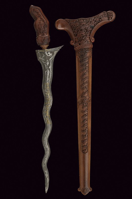 A kris with inscriptions in Arabic: dating: 20th Century provenance: Indonesia Undulated, double-edged blade featuring silver decorations and inscription in gold; wooden grip carved with inscriptions in Arabic, copper mendak; wooden wra