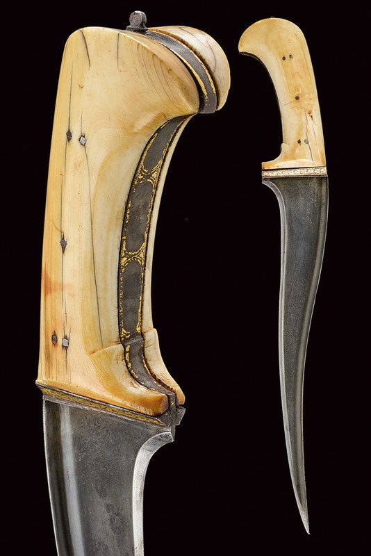 A fine pesh kabz: dating: 18th Century provenance: India Curved, single-edged blade made of fine Kara Korrasan damask, wide, "T"-back with a Hindi inscription, the grip with gilt frames (parts missing) and ivory grip s