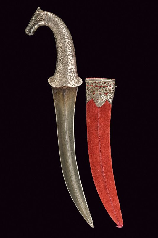 A kandshar: dating: 19th Century provenance: India Curved, double-edged, damask blade with central raiser; silver hilt richly engraved with floral motifs, the pommel shaped as a horse head. Wooden scabbard with r