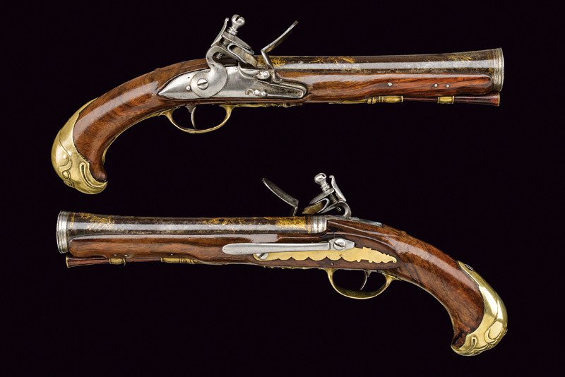 A fine pair of officers flintlock pistols: dating: circa 1800 provenance: Torino Round, smooth barrels, enlarged at the nozzle, engraved and gilt with crowned trophy and badge on blue ground; engraved tangs; flintlocks with round plate; wooden