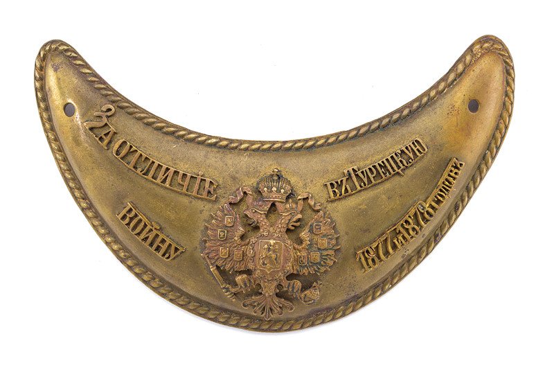 A gorget for bravery: dating: last quarter of the 19th Century provenance: Russia Made of bronze, in the shape of a convex crescent with fringed border; the Imperial Eagle at the center, among writings in Cyrillic (honor f