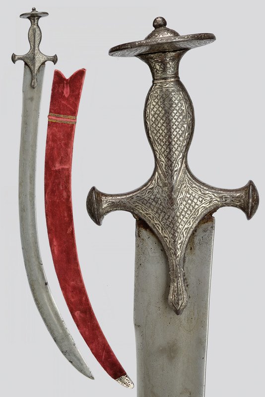 A thega (sabre): dating: circa 1800 provenance: India Wide, curved, damask, single-and false-edged blade with slight fuller and tang; typical, iron, tulvar hilt decorated with silver geometrical motifs; wooden scabbar