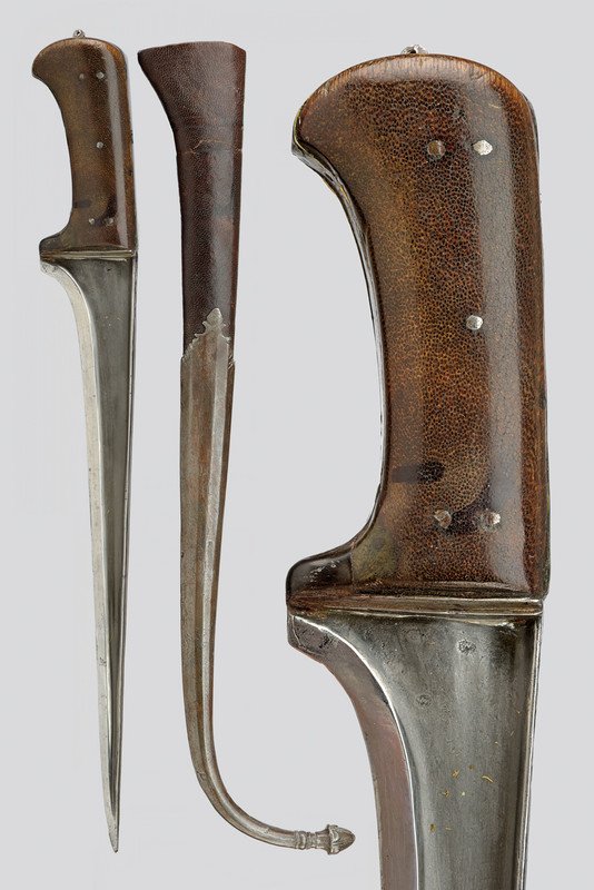 A karud (knife): dating: 19th Century provenance: Afghanistan Strong, straight blade made of fine, wootz damask and featuring "T"-back, with engravings and raisers. Grip with brown, fine leather grip scales. Wooden sc