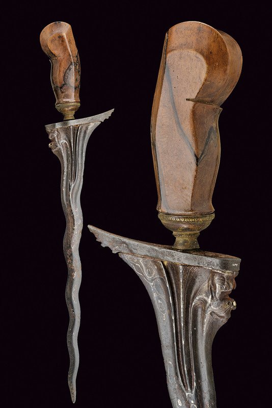 A kris: dating: 19th Century provenance: Bali Old, pamor, double-edged blade, carved and grooved with a monkey featuring silver mouth at the base.Wooden grip with brass mendak. dimensions: length 47 cm.