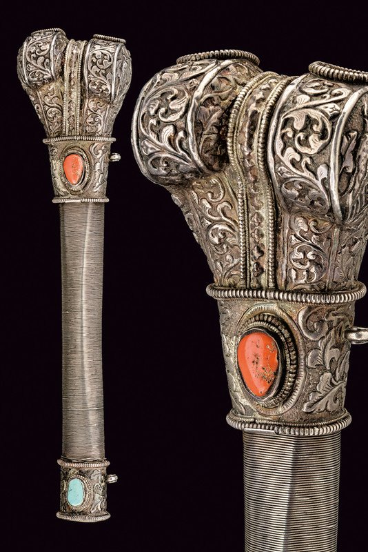 A silver trumpet: dating: circa 1900 provenance: Nepal The central part covered with silver wire; richly engraved with floral motifs, featuring two open-works and decorated with a red, cabochon stone (coral) at the fro