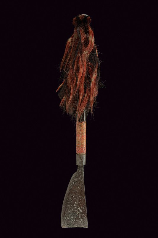 A Konyak war axe: dating: 19th Century provenance: India Iron head with wide, single-edged blade; long, wooden grip decorated with coloured, goat hair, the base bound by wicker bands. The Konyak is an important tribe o