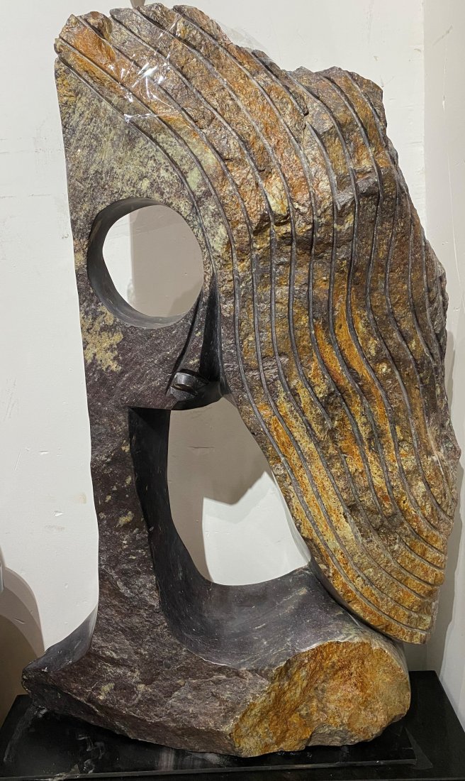 Large Shona stone sculpture by Witness Bonjisi: Large Shona stone sculpture by Witness Bonjisi, woman with flowing hair Signed W. Bonjisi on back Dimensions: 26"W x 39.5"H x 7.5"D Witness Bonjisi (Source: davidbarnettgallery) Witness Bonjesi was bo