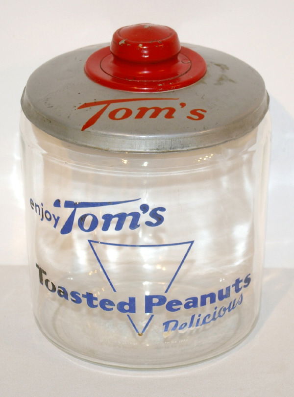 Tom's Glass Countertop Peanut Jar: Tom's Glass Countertop Display. Reads "Enjoy Tom's Toasted Peanuts Delicious." Measures 9 1/2" Tall.
