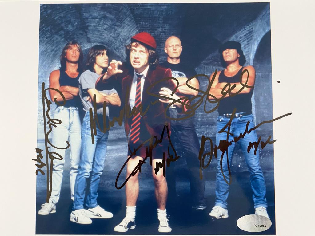 AC/DC Band Signed Photo: AC/DC band signed photo autographed by Brian Johnson, Angus Young, Malcolm Young, Cliff Williams and Phil Rudd. Measures 8.5x11.5 inches