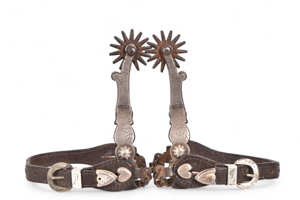 Mike Morales Marked Spurs w/ Chains: Features engraved card suit scene in silver mounted with "jello mold" concho along heelband and shank. Heart -shaped button hold leather straps of the period in place. 2" rowels