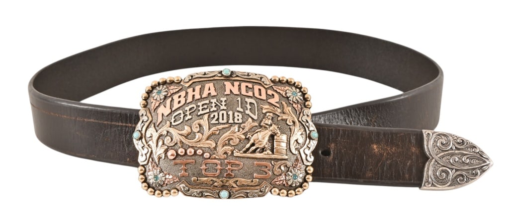 Yellowstone Laramie's Screen Worn Belt And Buckle: Buckle is an ornate, two-tone from the National Barrel Association (NBHA) 2018 Open 1D event. Top 3 finisher. Ornate belt tip. Buckle measures 4" x 3". Ariat belt measures 35 1/2" x 1 3/8".