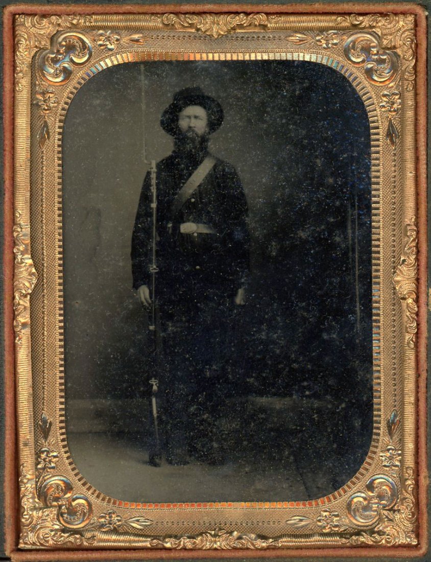 UNION SOLDIER & RIFLE & BAYONET CASED TINTYPE: Cased tintype. This Union Private is full standing. He holds either a Model 1855 or a Model 1861 Percussion Rifle-Musket in caliber .58 fitted with a bayonet. Split full case. In response to a questio