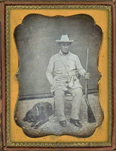 HUNTER, DOG, SHOTGUN & POWDER HORN DAGUERREOTYPE: Quarter plate daguerreotype.The rough and tough hunter looks sternly at us, holding his shotgun rifle aloft. We see his powder horn at his waist, and his trusty hunting dog on the floor. Great