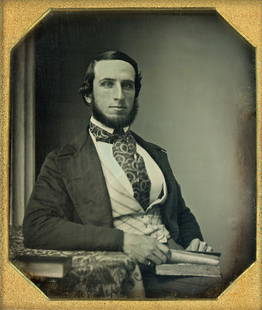 [Daguerreotype] Stunning Early Southworth and Hawes: Sixth plate. A striking pose of a young man with huge paisley cravat and patterned vest. He stares intently at the camera, his finger marking a place in a book in his lap as if he has just looked up