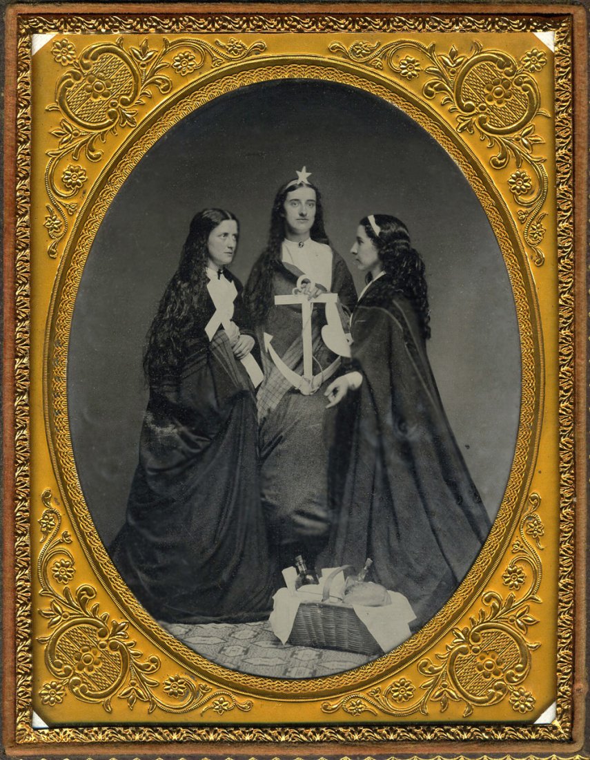 ALLEGORICAL ANCHOR SCENE: Half plate Ambrotype. Split case. Three young women pose for an allegorical scene. Left to right, they're holding a cross, an anchor, and a heart. The woman in the middle has a star on her head. The w