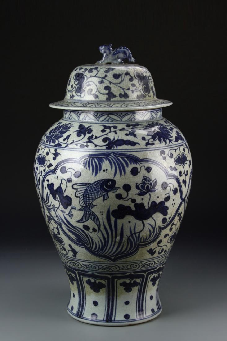 Chinese Blue and White Jar: China, blue and white jar with cover, with high rounded shoulders, with central image of a fish amongst lotus flowers and other auspicious symbols. Height 22 in.