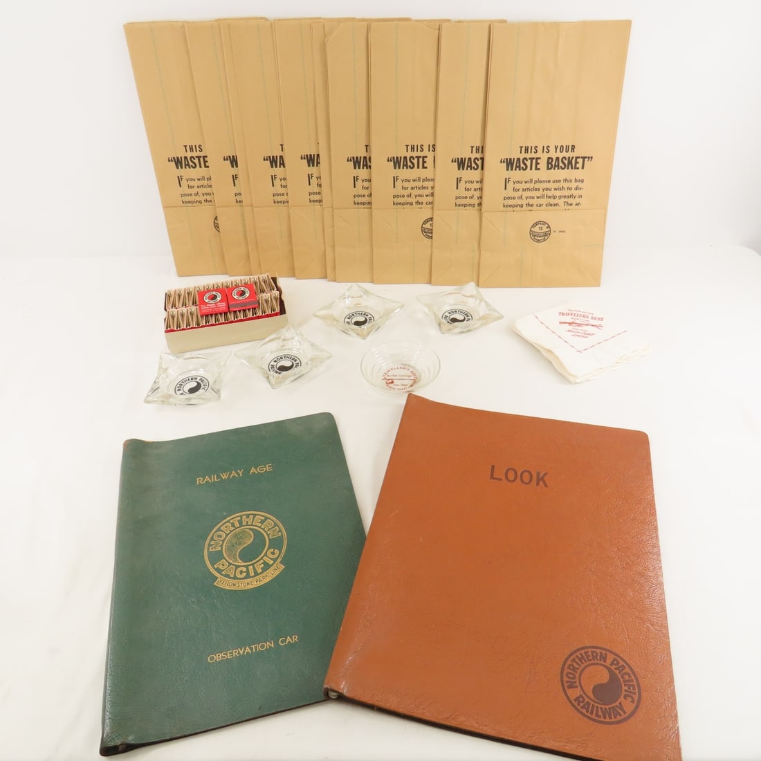 Northern Pacific Ashtrays, Magazine Covers & More: brown leather "LOOK" cover, green leather "Railway Age" cover- Yellowstone logo, 4 NP ashtrays, 1 traveler's rest ashtray and a handful of cocktail napkins, 1 box of Vista-Dome matchbooks, handful of 