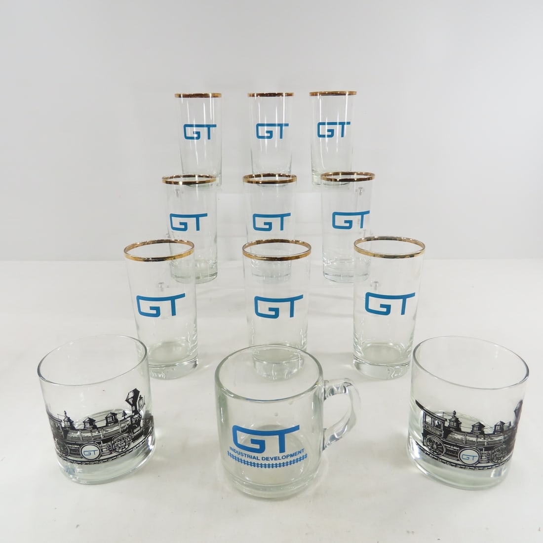 Grand Trunk Railroad Blue Logo Glassware: 9 5.5" gold edged tumblers, GT Industrial Development coffee cup, and 2 locomotive GT low balls. From the Collection of Don L. Hofsomer. Please ask questions and read terms & conditions before bidding