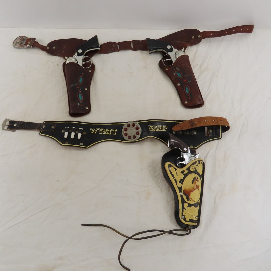 3 Vintage Nichols Cap Guns and Holster Belts: 3 Vintage Nichols Cap Guns and Holster Belts - 2 Cowhand in Texas Ranger leather holster belt, single Tophand in Wyatt Earp holster belt, all work Please ask questions and read terms & conditions befo