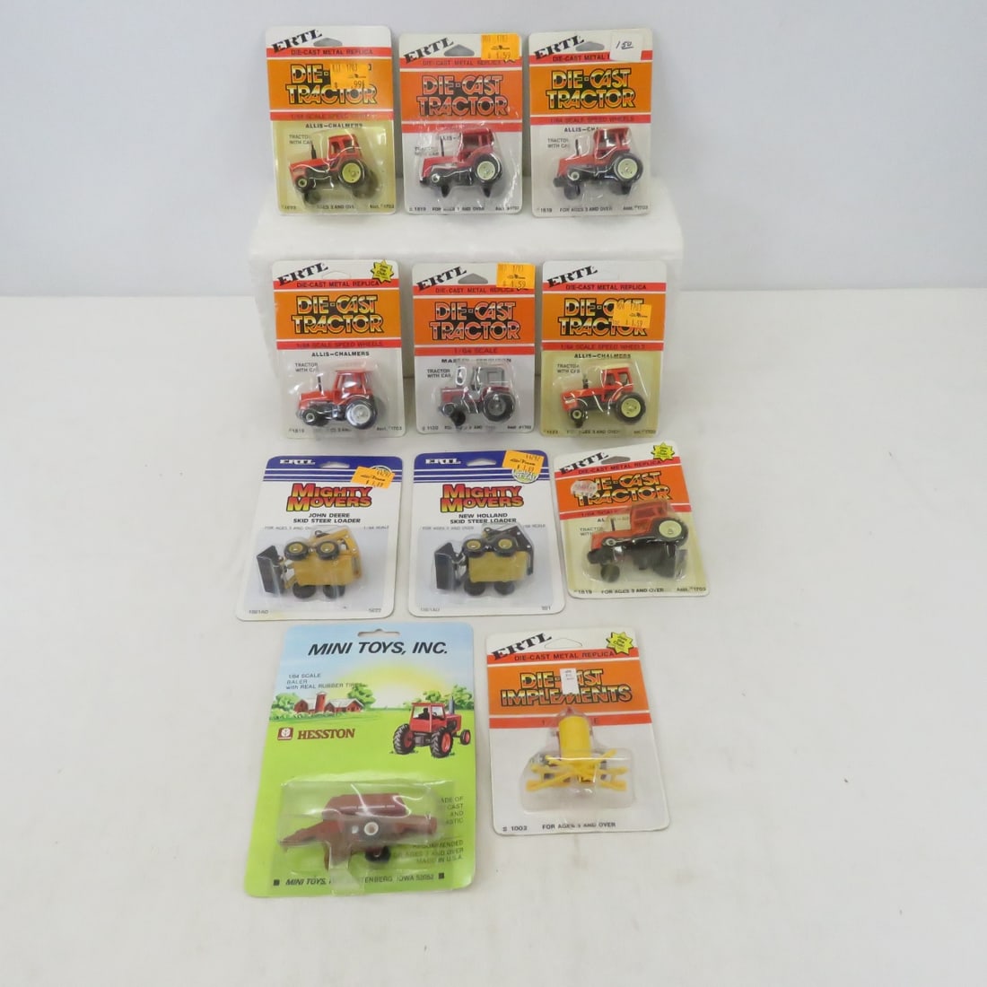 11 Die Cast Tractors and More, NIP: 11 Die Cast Tractors and More, NIP - 6x Allis Chalmers Tractors, 1 Massey Ferguson Tractor, 1 John Deere Skid Steer Loader, 1 New Holland Skid Steer Loader, 1 Hesston Baler, 1 Sprayer, All New on Card