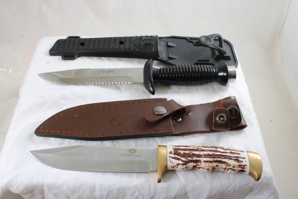 2 Fixed Blade Knives in Sheaths: 2 Fixed Blade Knives in Sheaths - Mossy Oak & Eternal Diving Knife. Lot Size 12" x 4" x 2". 1 1/2 Lbs. Photos are part of description (Live Auctioneers only shows up to 20). Please ask questions
