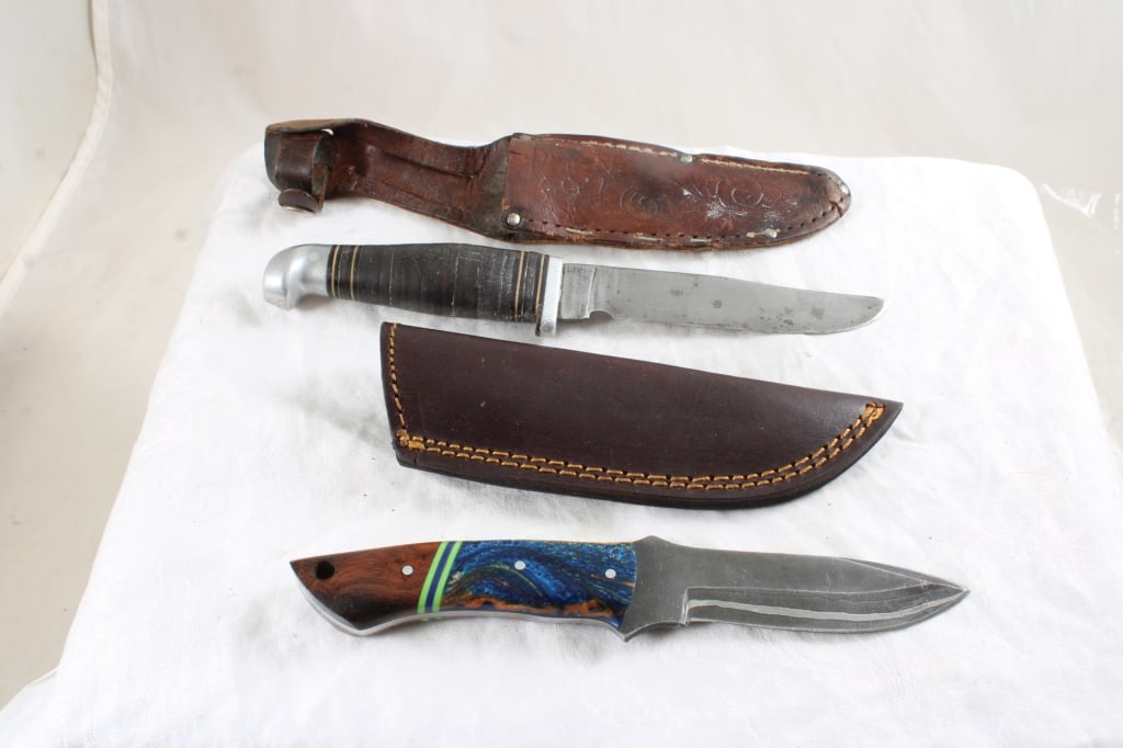 2 Fixed Blade Knifes in Leather Sheaths: 2 Fixed Blade Knifes in Leather Sheaths - 1 Custom Made and 1 Factory Made. 1 Lb. Lot Size 10" x 4" x 4". Photos are part of description (Live Auctioneers only shows up to 20). Please ask questions an