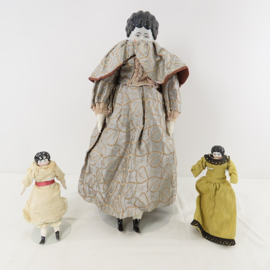 17" and 2 7" German China Head Dolls: 17" and 2 7" German China Head Dolls - All porcelain shoulder heads, hands and feet with cloth bodies. 17" and the 7" in gold dress are marked Germany, the other 7" is marked 6 and has wear of