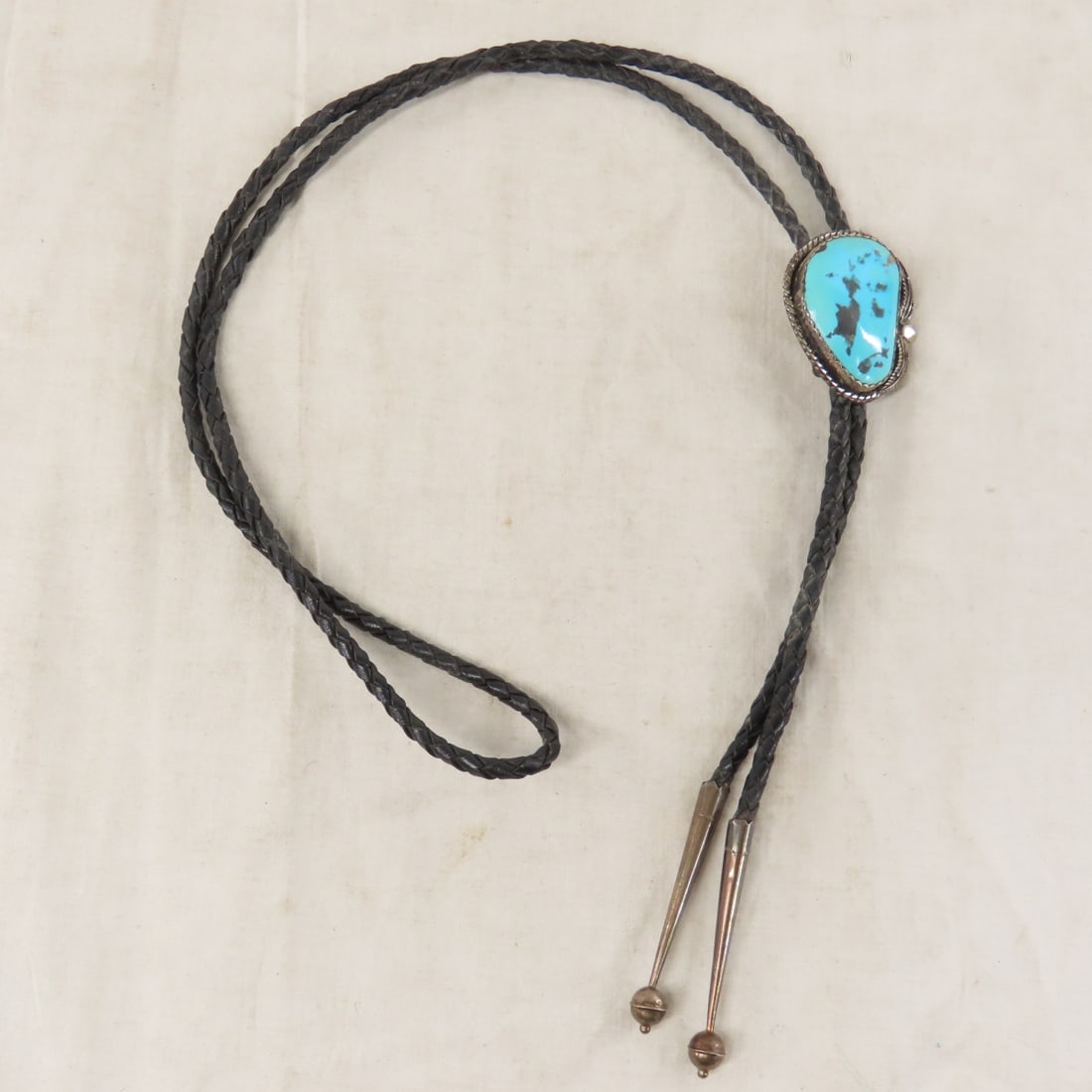 Signed Sterling Silver Turquoise Bolo Tie: Signed Sterling Silver Turquoise Bolo Tie - marked "L sterling, could be one of several different American Indian artists, on leather cord with unmarked silver tips. Lot size: 4x3x3", 3 oz Photos